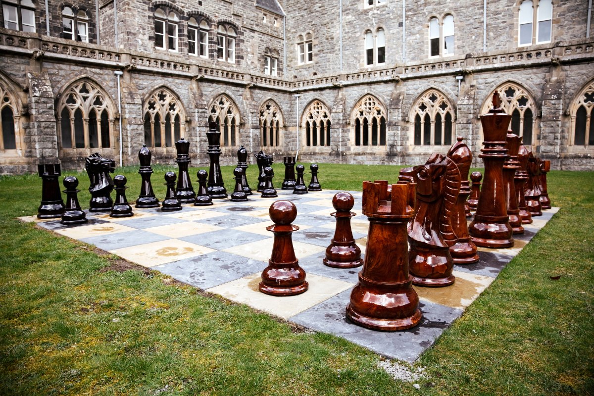 giant chess made from wood with a medieval castle in background 