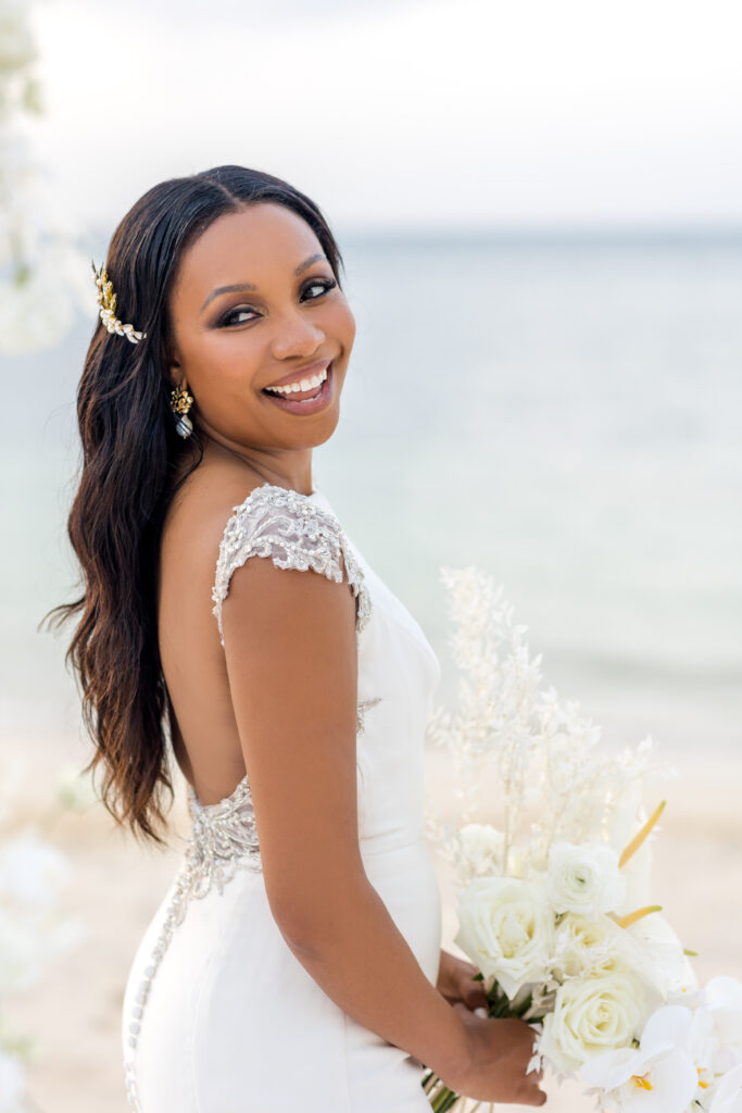 wedding in aruba with black bride standing by the ocean with a white bouquet