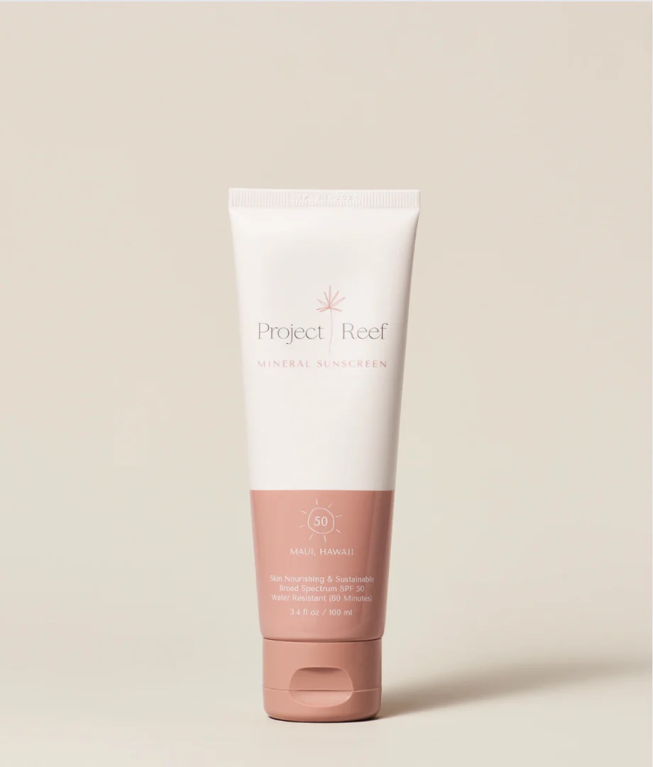 A tube of Project Reef Mineral Sunscreen with SPF 50, designed for skin nourishment and sustainability. The tube is white with a pink cap and text.