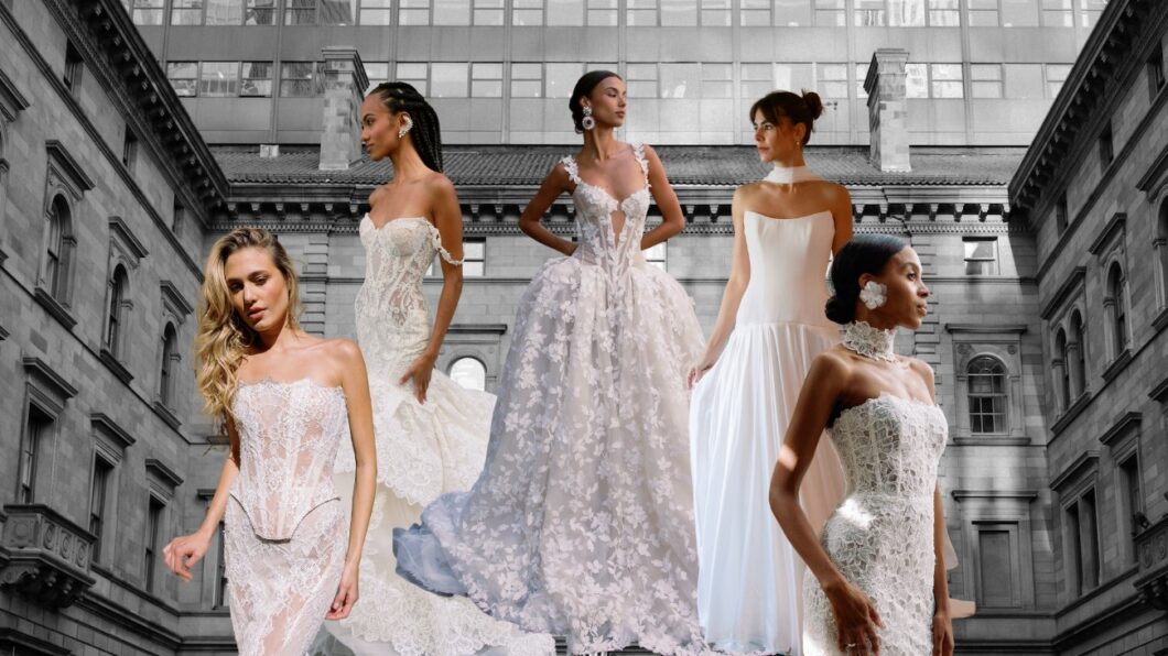 Five models in various bridal gowns stand in front of a historic building with large windows.