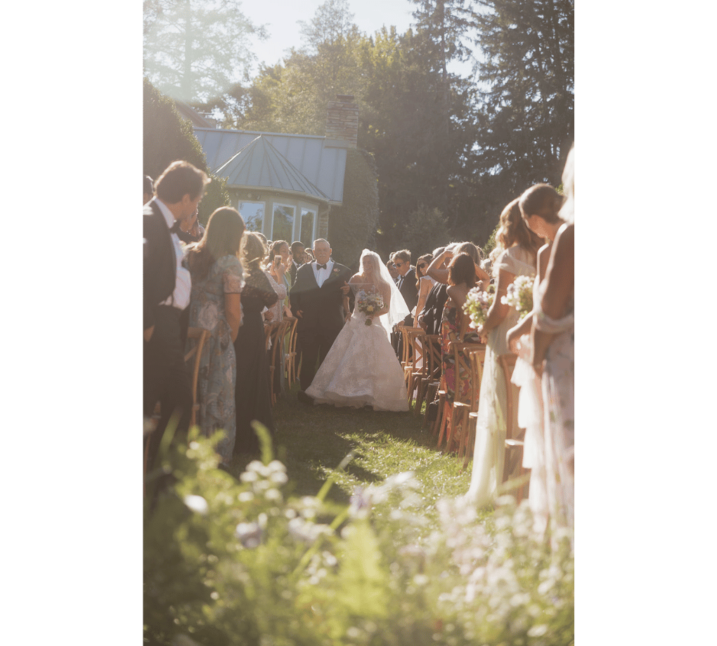 A bride walking down a aisle with a crowd of people.