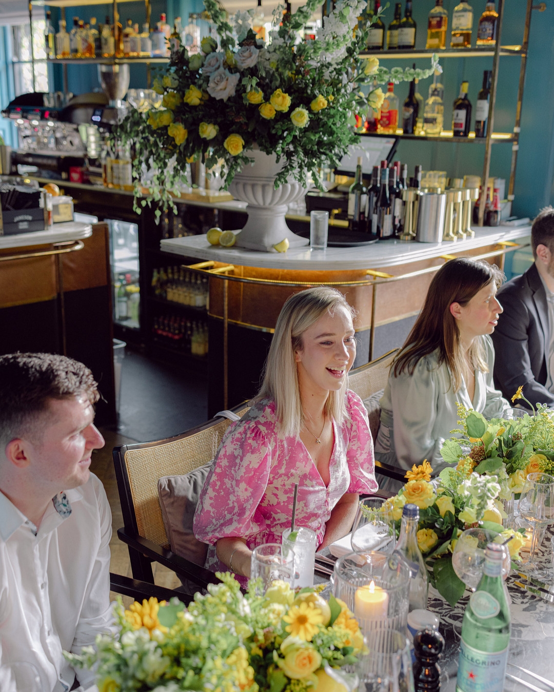 People sitting at a table with floral decorations, dining in a restaurant.