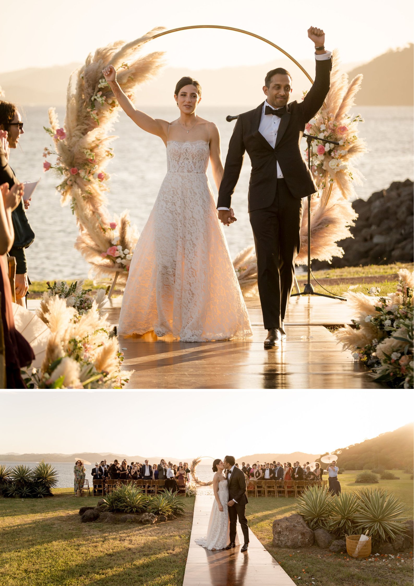 A bride and groom walk down an outdoor aisle by the water, holding hands and celebrating, with guests seated in the background.