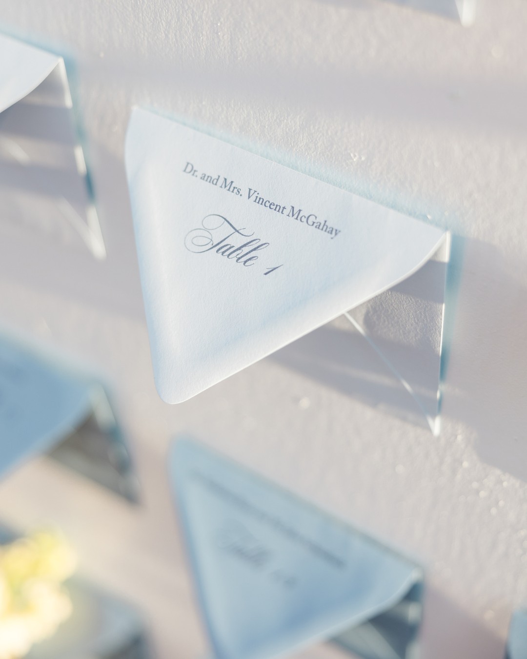 A triangular folded card labeled "Table 1" with the name "Dr. and Mrs. Vincent McLuhan" is attached to a white wall.