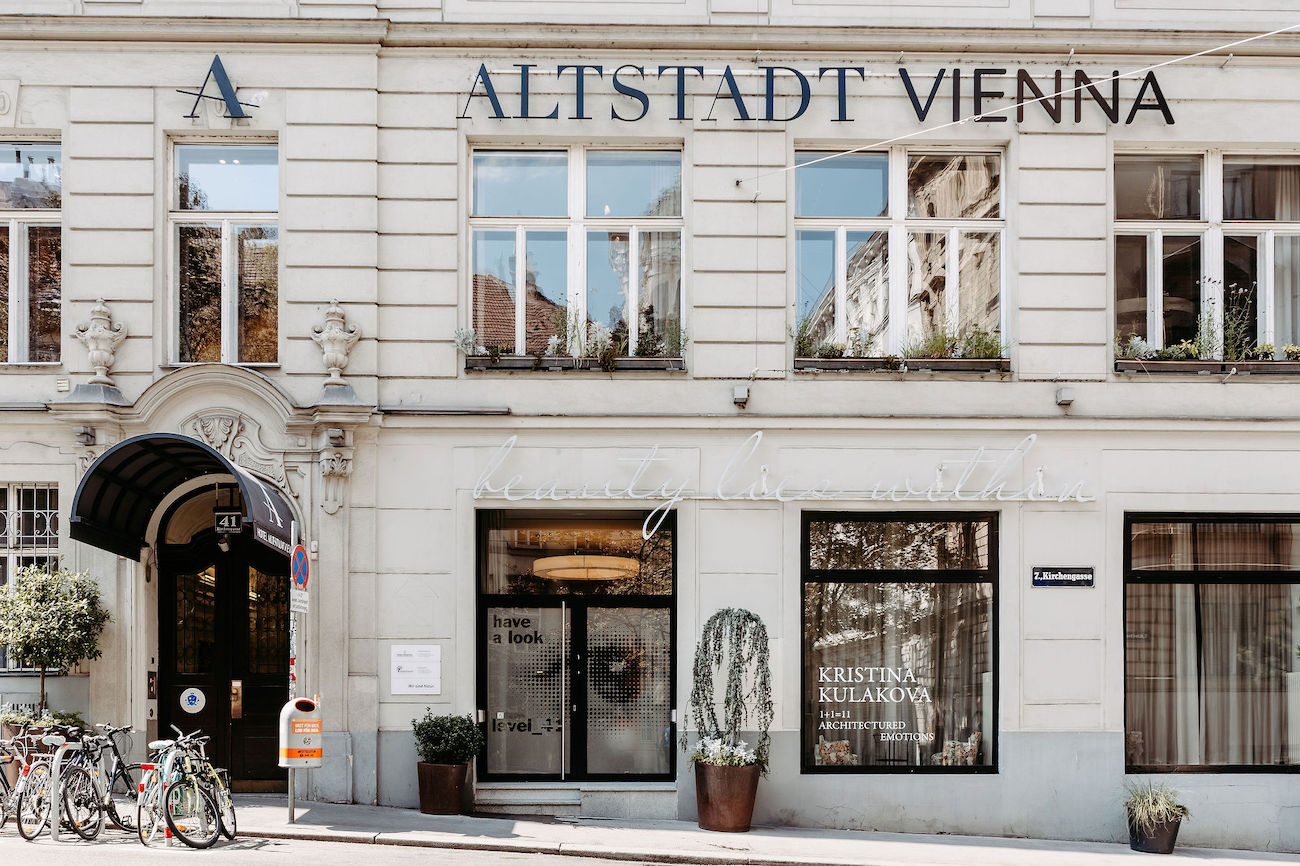 Facade of Hotel Altstadt Vienna, featuring large windows, a main entrance, and a row of parked bicycles on the sidewalk.