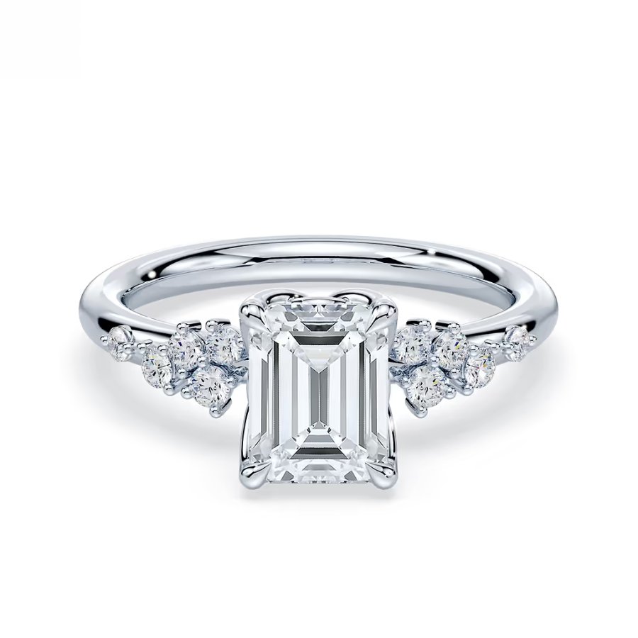 A white gold ring featuring an emerald-cut diamond center stone with smaller round diamonds set on each side.
