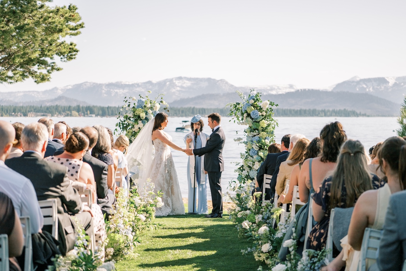 A bride and groom share a moment on the shores of Lake Tahoe with the mountains and blue water in the background.