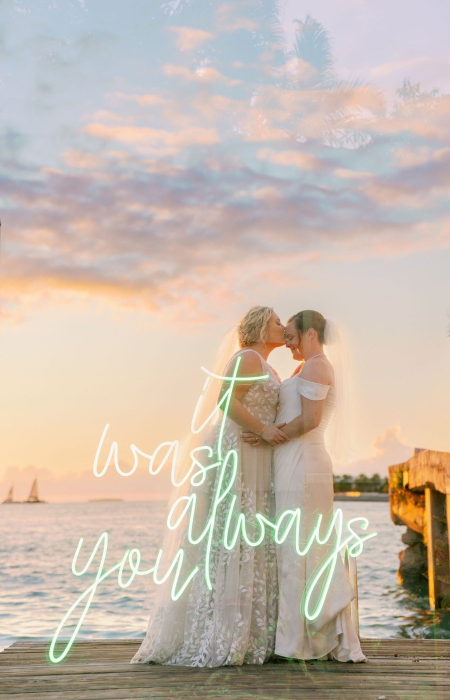 Two women in wedding dresses embrace and kiss on a wooden pier at sunset, with the words “It was always you” written in cursive over the image.