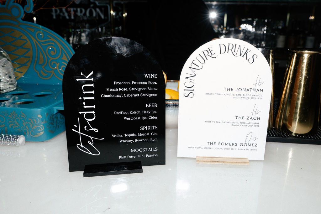 Two drink menus displayed on a bar counter, listing various wines, beers, spirits, cocktails, and signature drinks.