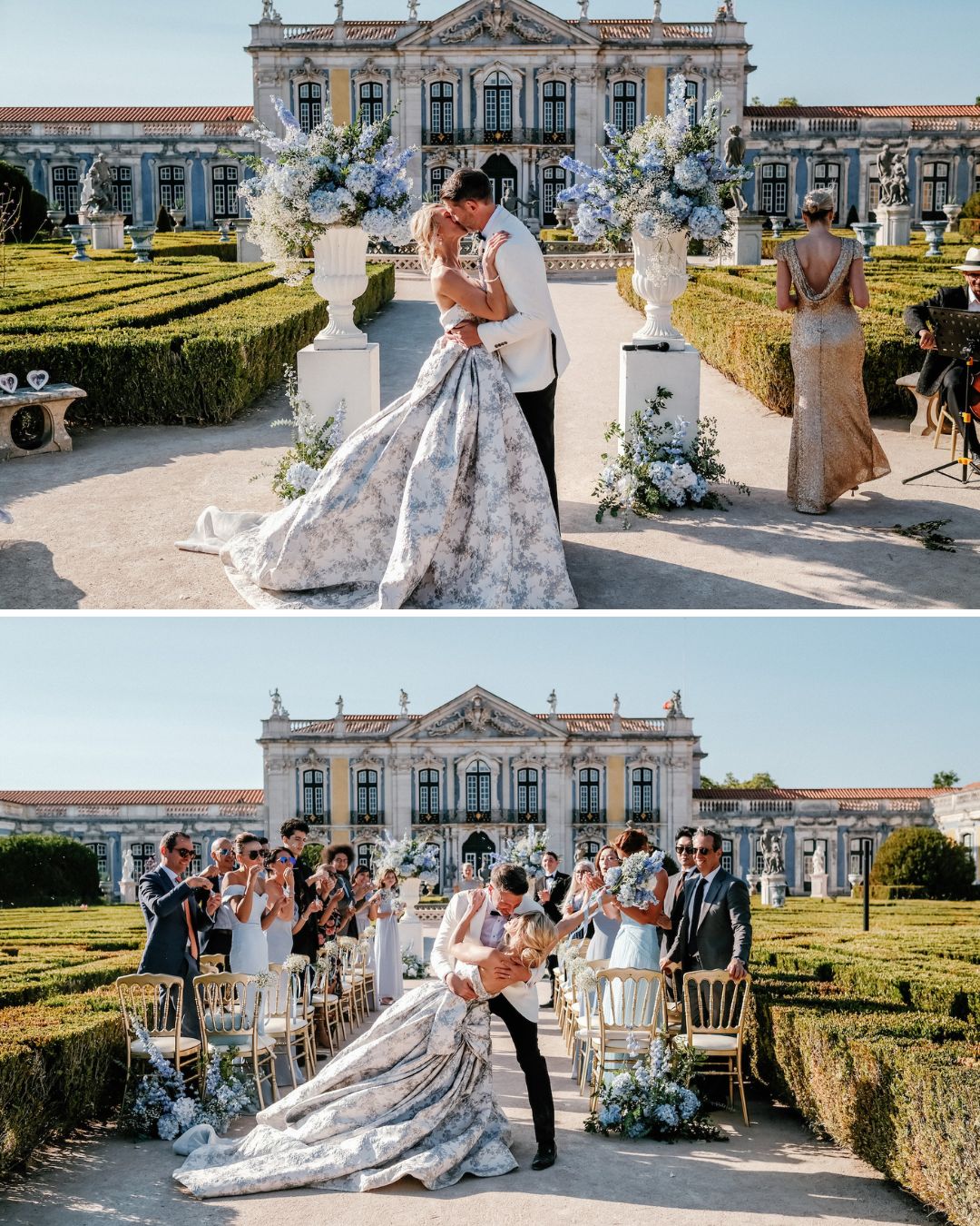 A bride and groom kiss at an outdoor wedding ceremony in front of a historic building, surrounded by guests, flowers, and manicured hedges.