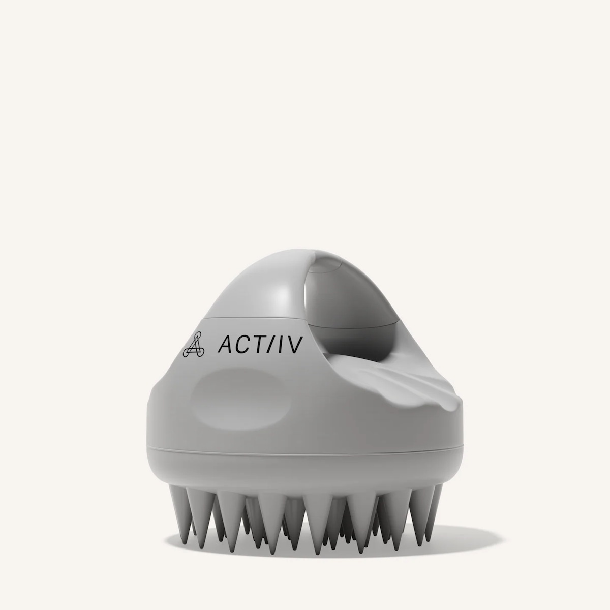 A gray silicone scalp massager with a curved handle, short bristles on the bottom, and “ACT/IV” printed on the side, shown against a plain off-white background.