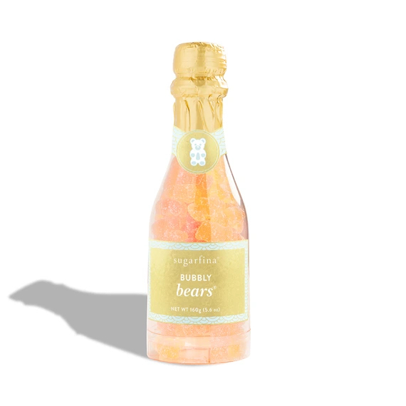 A small bottle of Sugarfina Bubbly Bears shaped like champagne, filled with champagne-flavored gummy bears.