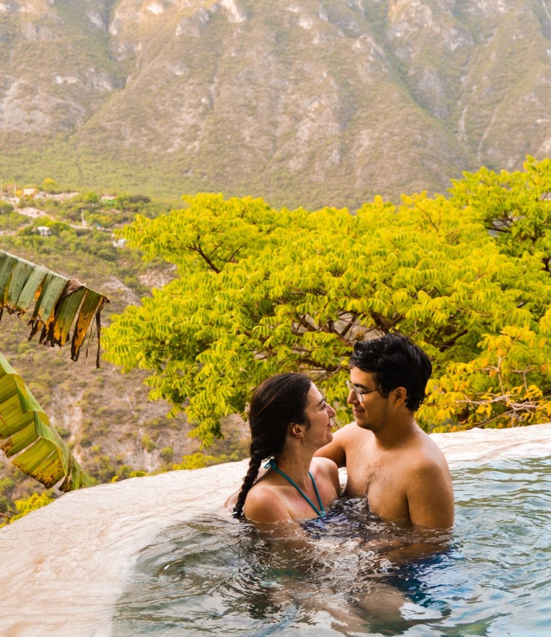 A couple embracing in an infinity pool overlooking a mountain landscape.