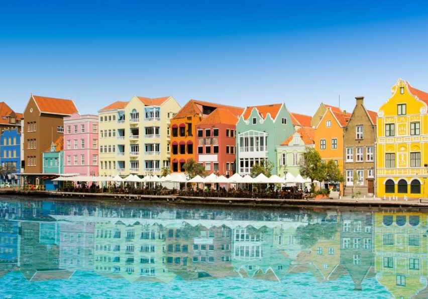 Colorful colonial buildings with gabled roofs flank a harbor in Willemstad, the capital city of Curaçao.