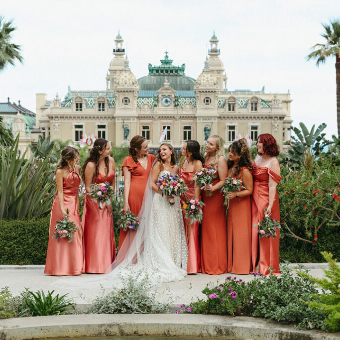 bride in front of St. Charles Church in Monaco with bridesmaids in salmon dresses