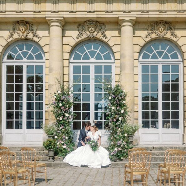 Wedding couple sit at altar in front of Chateau de Champlatreux