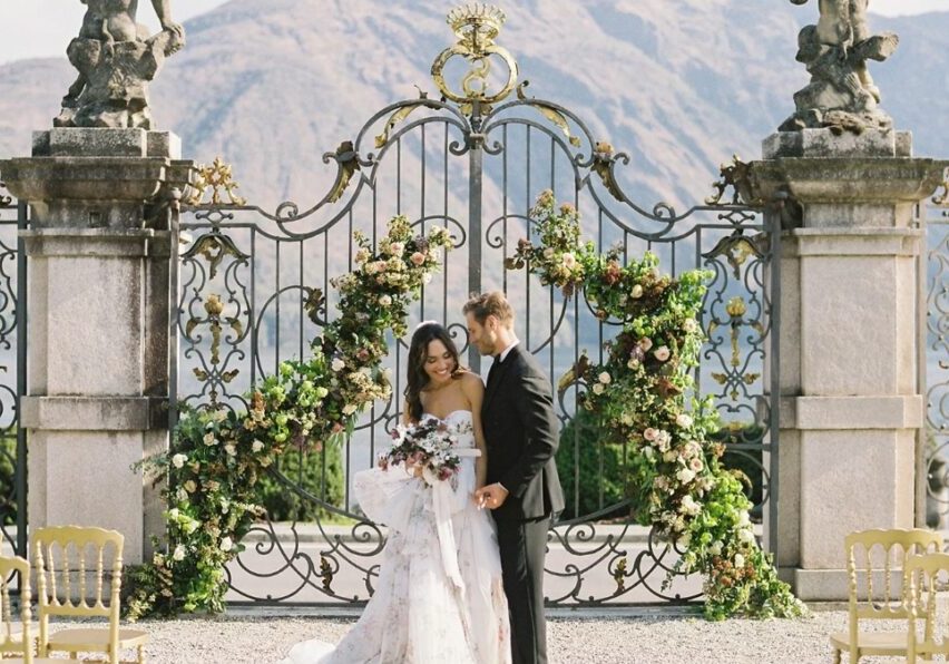 A bride and groom in front of wrought iron gates in lake Como