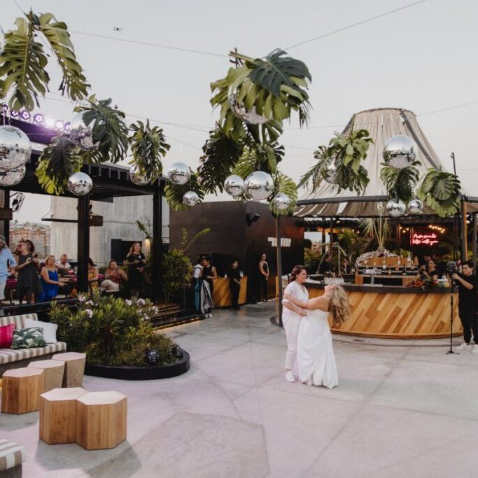 the brides dance under a stringed canopy of disco balls and palm fronds
