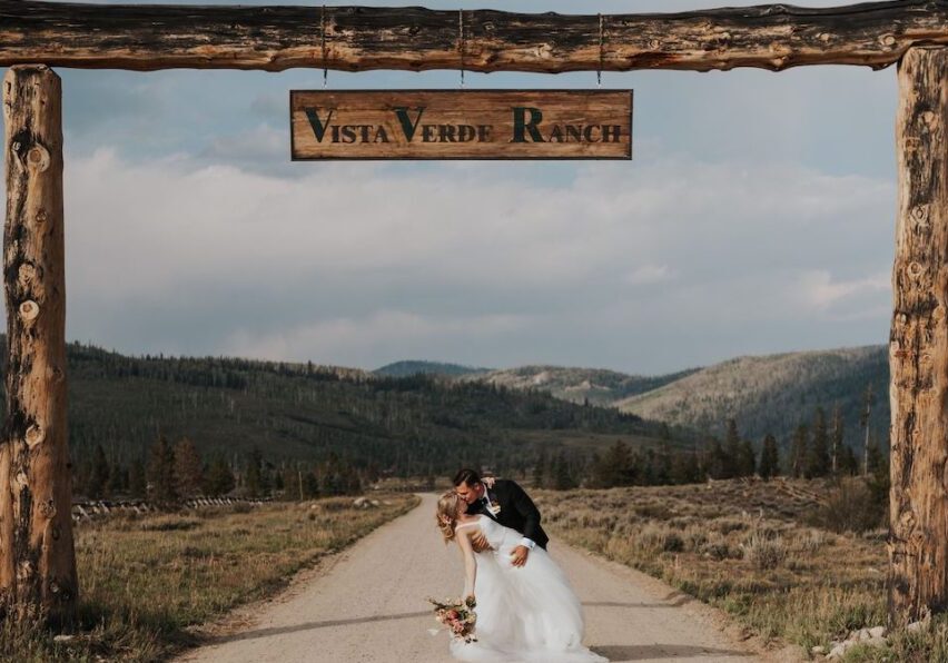 bride and groom kiss under the wooden Vista Verde Ranch