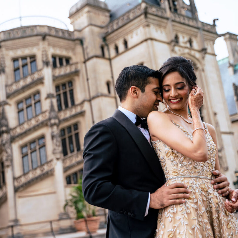 Indian bride and groom embrace in front of Biltmore Estate