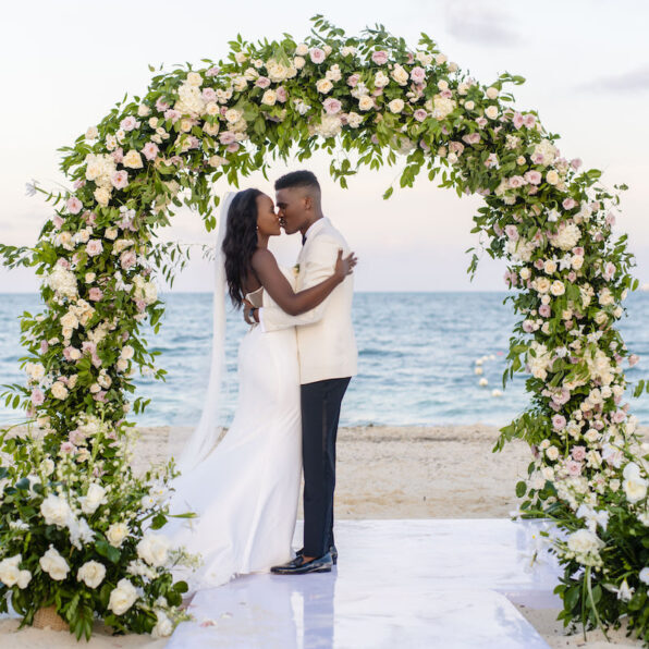 Couple under wedding arch on beach