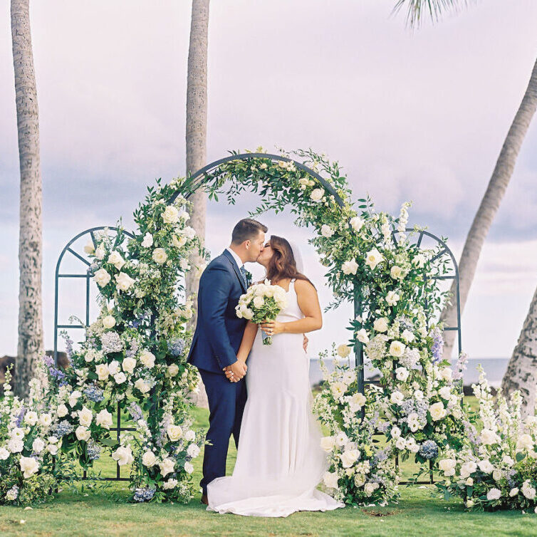 bride and groom under floral arch