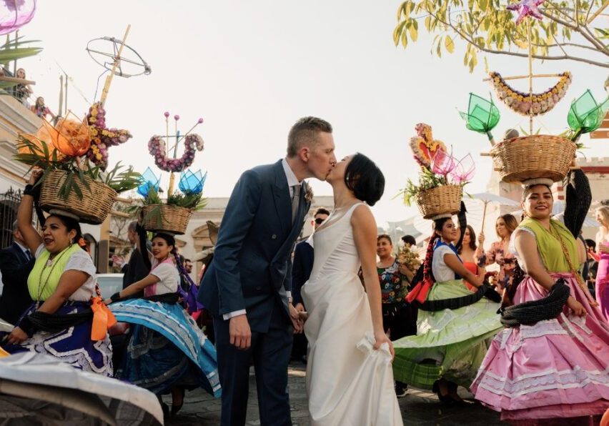 couple kissing as women in Mexican dresses twirl around them